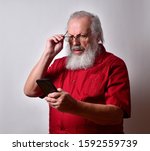 Small photo of Old man in bright red shirt with long white beard reacting to to the news that he lost his dead end job. His job got the axe and now he may have to go on the dole.