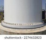 Small photo of Close up wind turbine foundation or base has grout cement, anchor bolts and plastic caps.
