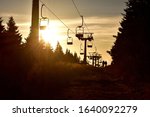 People walks under ski chair lift in the mountains at sunset. Romantic view.