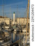 Small photo of LA ROCHELLE, FRANCE - AUGUST 26, 2022: Port of La Rochelle with lighthouse and typical buildings facades in the bacground at sunset, France.