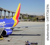 Small photo of Phoenix, Arizona / USA - February 15, 2016: Colorful tail end of a jet sitting on tarmac with elevated railway next to it.
