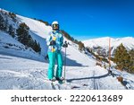 Portrait of a woman skier with ski on, looking at camera with slopes behind, Pyrenees Mountains. Winter ski holidays in El Tarter, Grandvalira Andorra