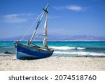 Small photo of Old wooden fishing boat on deserted beach, turquoise sea in the background. Chrissy beach, Crete.