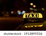 A close-up shot of a taxi sign in the night with bokeh lights in the background
