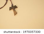 A closeup shot of a wooden tau cross necklace isolated on a brown background