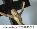 Small photo of A closeup of a crucified Jesus statue on a wooden croon a white background