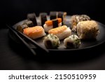 Sushi on black plate with black chopsticks dark background