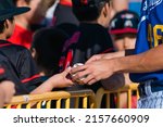 Small photo of BAKERSFIELD, UNITED STATES - Feb 28, 2022: The California State University Bakersfield player signs a baseball for a young fan