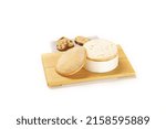 Small photo of A wooden plank with a cut truckle of cheese with slices and bread isolated on the white background