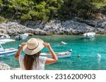 Young woman in beach clothes and sun hat near idyllic cove with boats and turquoise sea at Rasohatica beach on Korcula island in Croatia