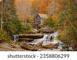 An old mill situated behind a waterfall surrounded by autumn foliage New River Gorge National Park