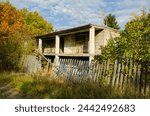 Small photo of fallen old wooden fence, worn-out pickets of old wooden fence, old ladder and abandoned unfinished cinder block house, abandoned house, abandoned family place