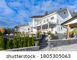 Small photo of Beautiful white stone house. Two storey country house Villa cottage residence with a large balcony. Scandinavian garden design. Green thuja. Stone fence. Carport.