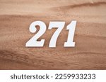 Small photo of White number 271 on a brown and light brown wooden background.