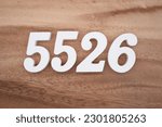 Small photo of White number 5526 on a brown and light brown wooden background.