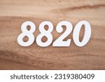 Small photo of White number 8820 on a brown and light brown wooden background.