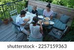 Family eating lunch in home backyard wooden patio. Top view of people gathered for meal outdoros