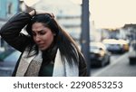 Small photo of Worried young woman walks in street shaking head in disbelief. Preoccupied female person in 20s feeling frustration and stress during difficult times