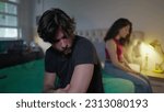 Small photo of Unhappy couple feeling disconnected from each other. Man and woman sitting in bed ignoring each other