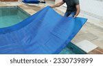 Small photo of Man removing swimming pool cover and folding protector