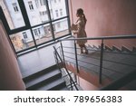 Top view full length serene female coming downstairs in apartment. Indoor concept