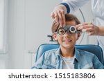 Smiling child boy in glasses checks eye vision at pediatric ophthalmologist
