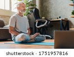 Middle aged sport man doing yoga and fitness at home using laptop