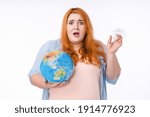 Small photo of Disquieted overweight woman holding globe and plastic bottle isolated over white background