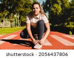 Small photo of Plump plus-size body positive woman athlete tying sporty shoes, active wear, sneakers for training workout jogging running in stadium outdoors.