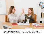 Small photo of Successful young tutor teacher mother babysitter nanny helping her daughter student schoolgirl with homework, test, exam, new topic giving high five at home school.