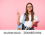 Small photo of Excellent best student schoolgirl pointing with her fingers showing copy space wearing school bag isolated in pink background
