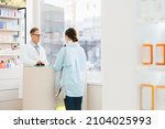 Small photo of Mature middle-aged male caucasian chemist pharmacist druggist explaining advising drugs, painkillers, antibiotics, consulting female customer client buyer in pharmacy drugstore