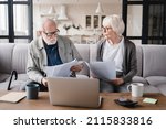 Small photo of Serious elderly senior grandparents couple family wife and husband counting funds, savings, declarations, investments,paperwork, financial documents, bankruptcy, court case, bills, pension at home.