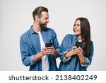 Small photo of Young mobile users, loving couple spouses girlfriend and boyfriend using smart phones together looking at each other, surfing on internet online, e-commerce, e-banking isolated in white background