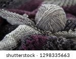 Small photo of A ball of grey yarn or wool resting on knitting showing different stictches and textures. Crafting, knitting, make do and mend, hand craft concepts.