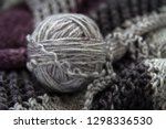 Small photo of A ball of grey yarn or wool resting on knitting showing different stictches and textures. Crafting, knitting, make do and mend, hand craft concepts.