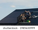 Installing new black solar panels on the metal roof of a private house. Ecology, renewable energy and green sustainable source of power abstract.