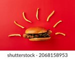 Small photo of French fries as aureole and burger on red background. Minimal food concept