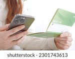 Small photo of A woman staring at the bankbook On the cover of the passbook, it is written as "savings account" in Japanese.
