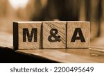 Small photo of Wooden cubes with the abbreviation M and A on them. Business merges and aquisitions concept.