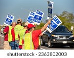 Small photo of Wentzville, Missouri, United States, September 18, 2023: United Auto Workers, UAW, on strike carrying signs walking picket line outside GM assembly plant in Wentzville, Missouri. Waving at cars.