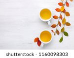 Two cups  of tea and colorful autumn leaves  on white rustic table.