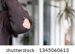 Small photo of Man with worn to holes fabric sweater with pipped sleeve - Person wearing rubbed old shirt with hole on sleeve - Ragged cloth hole elbow sleeve