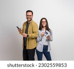 Smiling young man and woman holding credit card and smart phones against background. Cheerful couple wearing eyeglasses recommending electronic banking and online shopping