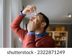 Small photo of Close-up of young man applying eye drops to treat dry eye and irritation at home