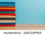 A simple composition of many hardback books, raw books on a wooden table and a bright blue background. back to school. Education.