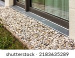 Small photo of Pebbles for water drainage along perimeter of house. Rainwater harvesting with drainage grid or Drain Grate.