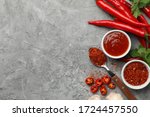 Composition with chilli pepper, powder spice, garlic and sauce on gray background