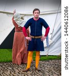 Small photo of A re-enactment medieval squire poses for the cameras will his wife complains about the leaking tent, The encampment