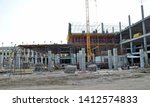 Small photo of The multi-storey building is being built slowly. Building materials on the third and first floor. Crane continues to build floors. Workers working on the roof. The building begins to take shape.